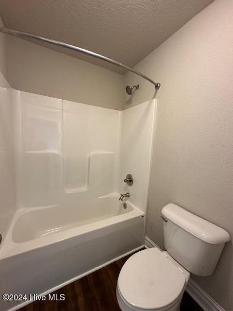 bathroom with hardwood / wood-style floors, tub / shower combination, toilet, and a textured ceiling