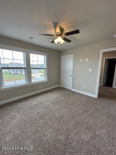 carpeted empty room featuring a textured ceiling and ceiling fan