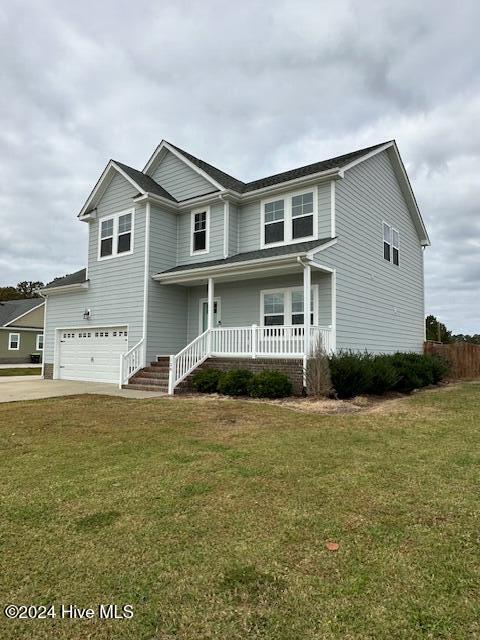 view of front of home with a front yard, a garage, and covered porch