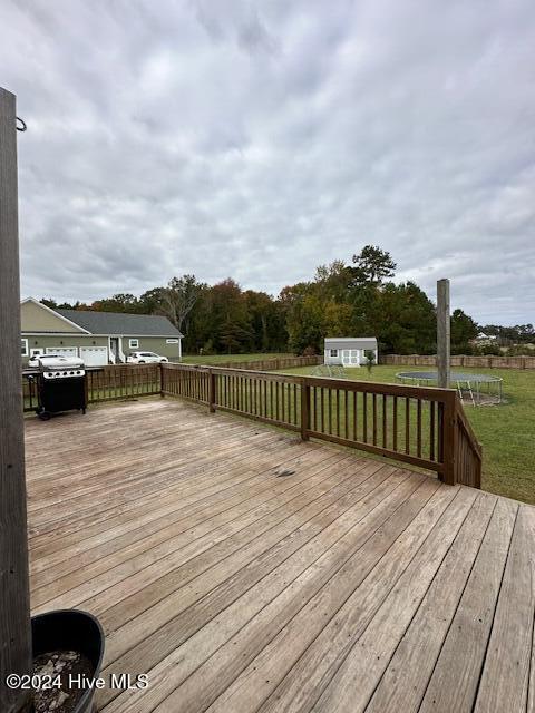 wooden terrace with a lawn and area for grilling