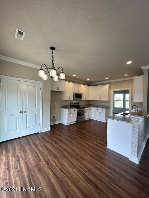 kitchen featuring kitchen peninsula, decorative light fixtures, appliances with stainless steel finishes, a notable chandelier, and white cabinetry