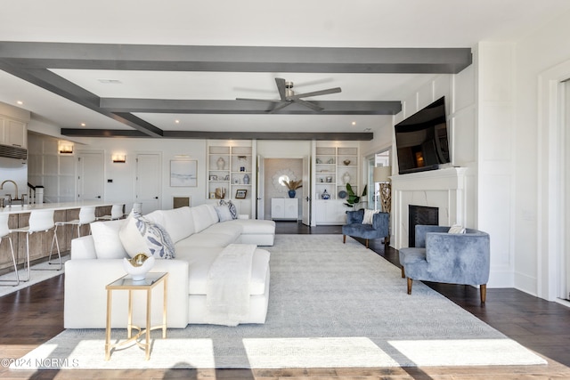 living room featuring beam ceiling, hardwood / wood-style flooring, built in features, and ceiling fan