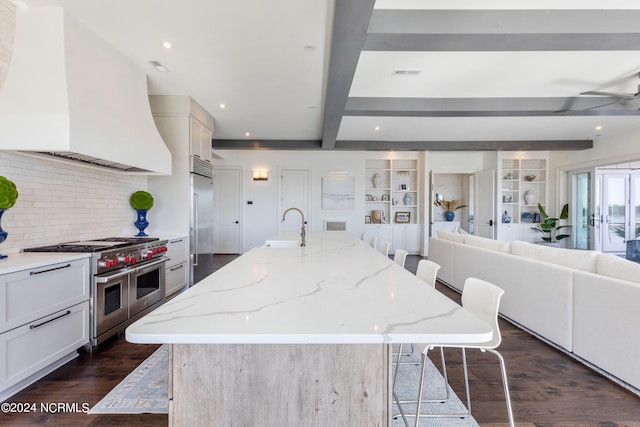 kitchen featuring beam ceiling, a large island, a kitchen bar, premium appliances, and premium range hood