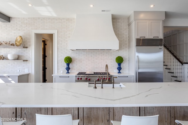 kitchen featuring appliances with stainless steel finishes, light stone countertops, and extractor fan