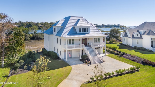 view of front of property featuring a porch, a front yard, a garage, and a water view