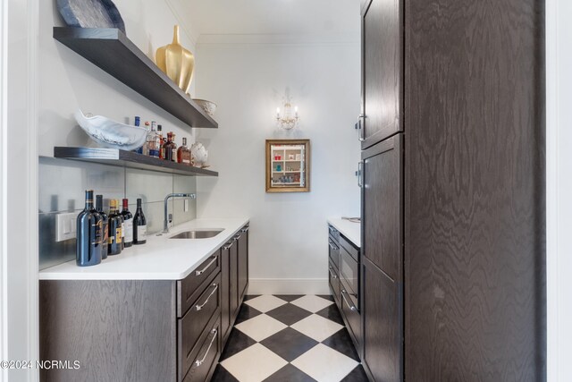 kitchen with ornamental molding, sink, and dark brown cabinetry