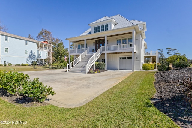 coastal home featuring covered porch, a front yard, and a garage