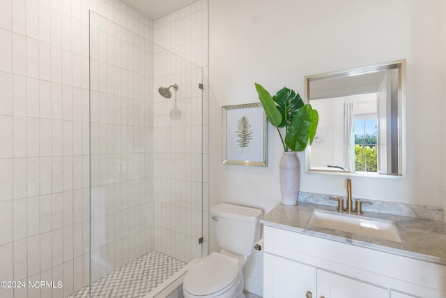 bathroom with toilet, vanity, and tiled shower