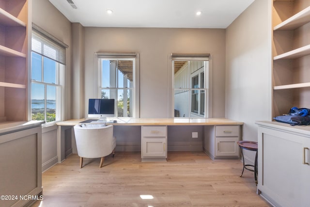 office area featuring built in desk, light hardwood / wood-style flooring, and a wealth of natural light