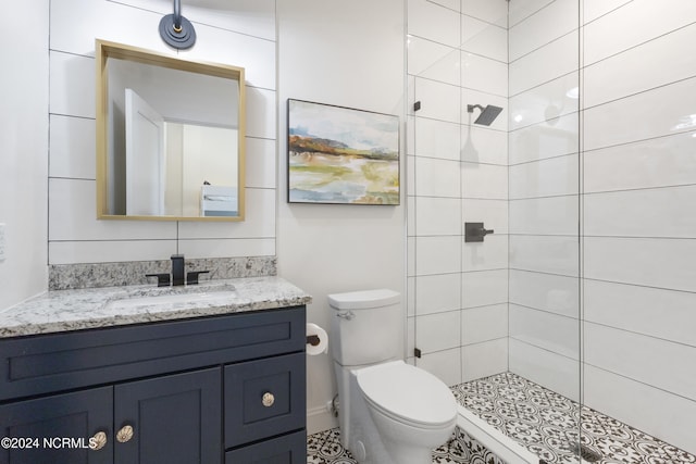 bathroom featuring toilet, vanity, and tiled shower