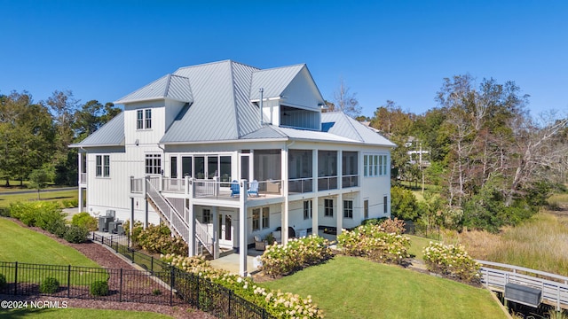 rear view of property with a sunroom, a patio area, a lawn, and central AC unit