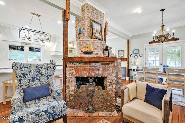 living room featuring french doors, crown molding, wood-type flooring, and a brick fireplace