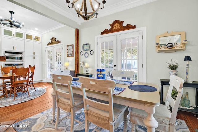 dining space featuring french doors, hardwood / wood-style flooring, a notable chandelier, and crown molding