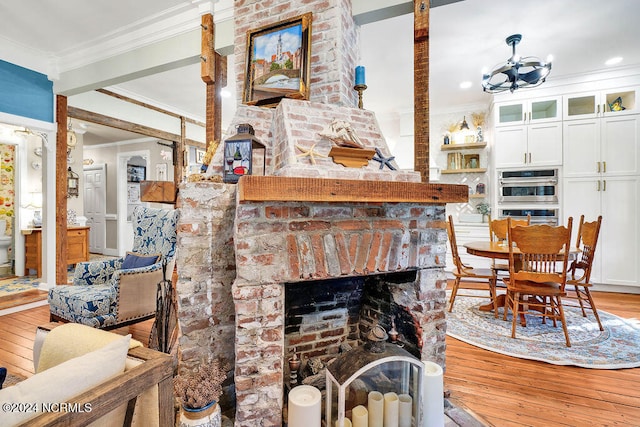 living room featuring light hardwood / wood-style floors, crown molding, a chandelier, and a fireplace