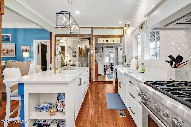 kitchen featuring sink, a kitchen island, hanging light fixtures, light hardwood / wood-style floors, and light stone counters