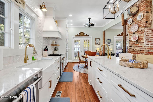 kitchen with brick wall, sink, pendant lighting, white cabinetry, and dark hardwood / wood-style flooring