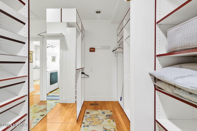 walk in closet with washer / clothes dryer and light wood-type flooring