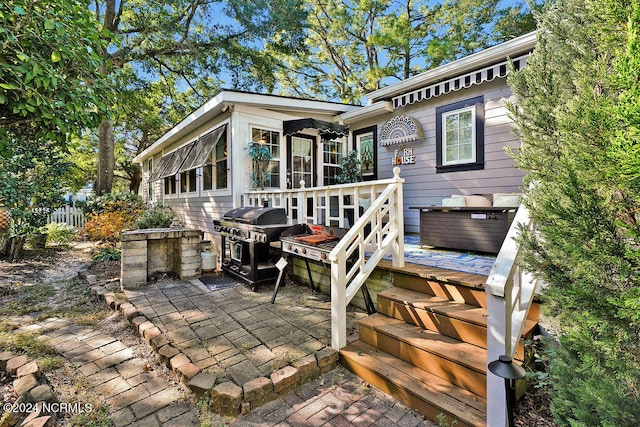 rear view of house featuring a jacuzzi, a patio area, and a wooden deck