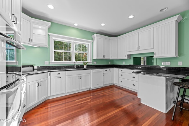 kitchen featuring white dishwasher, oven, white cabinets, and dark hardwood / wood-style flooring