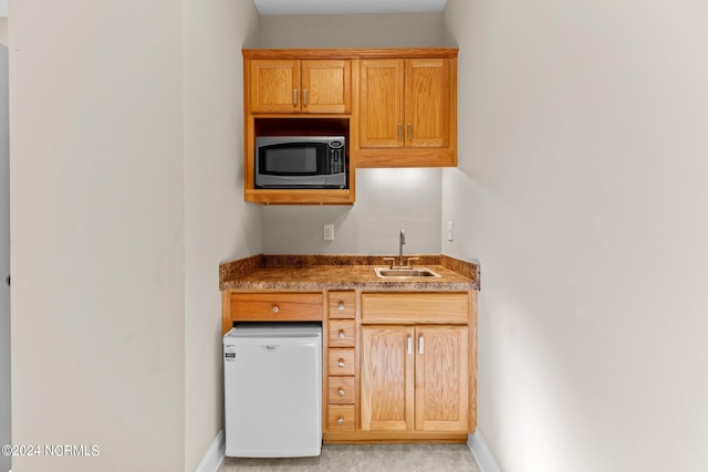 kitchen with sink, white fridge, and light colored carpet