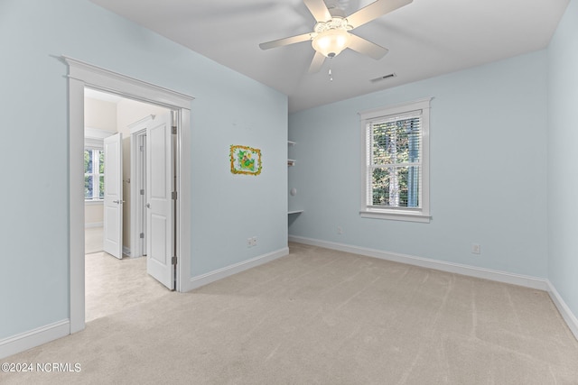 carpeted empty room with ceiling fan and a wealth of natural light