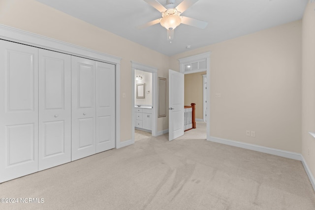 unfurnished bedroom with a closet, ensuite bath, light colored carpet, and ceiling fan