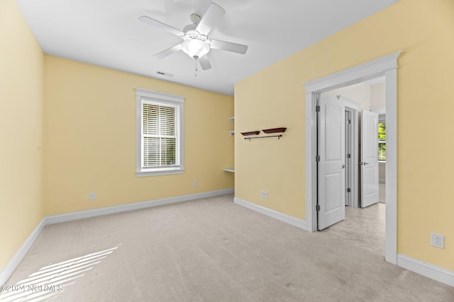 spare room with ceiling fan, a healthy amount of sunlight, and light colored carpet