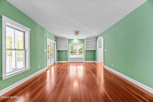 empty room featuring french doors, hardwood / wood-style flooring, and plenty of natural light