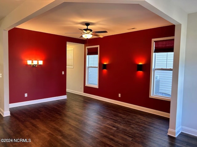 empty room with dark wood-type flooring, ceiling fan, and a wealth of natural light