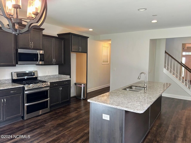 kitchen with sink, appliances with stainless steel finishes, dark wood-type flooring, and a kitchen island with sink