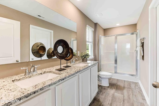 bathroom with wood-type flooring, toilet, vanity, and walk in shower