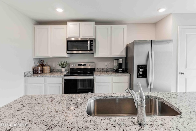 kitchen with light stone counters, sink, stainless steel appliances, and white cabinets