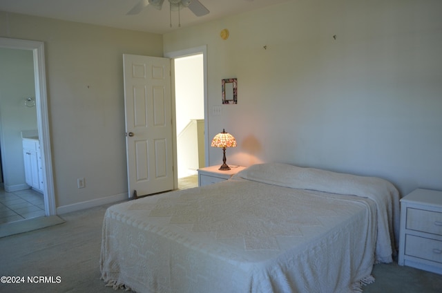 bedroom featuring light carpet, ensuite bathroom, and ceiling fan