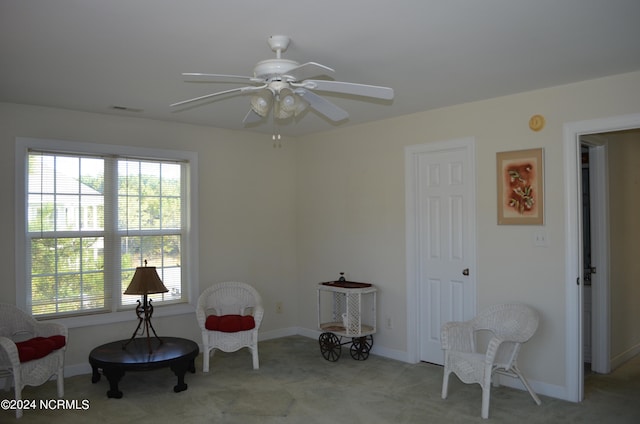 living area featuring light carpet and ceiling fan