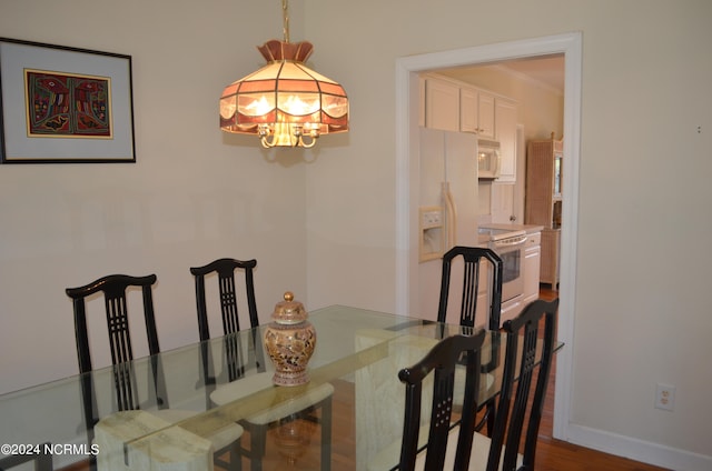 dining space featuring an inviting chandelier, ornamental molding, and dark wood-type flooring