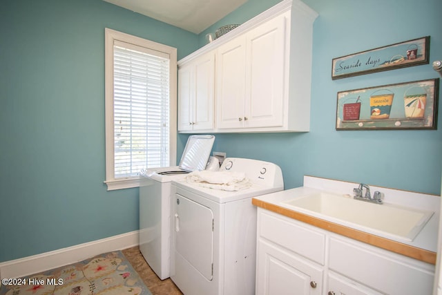 washroom with sink, light tile patterned floors, cabinets, and washing machine and clothes dryer