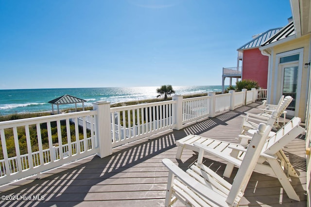 wooden deck featuring a water view and a beach view