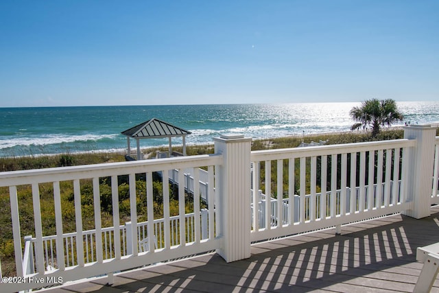 wooden terrace with a water view and a view of the beach