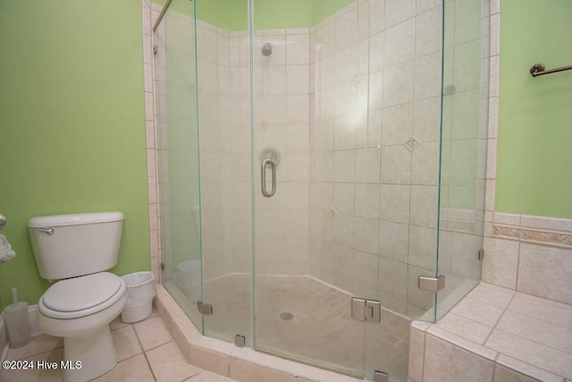 bathroom with a shower with door, tile patterned floors, and toilet