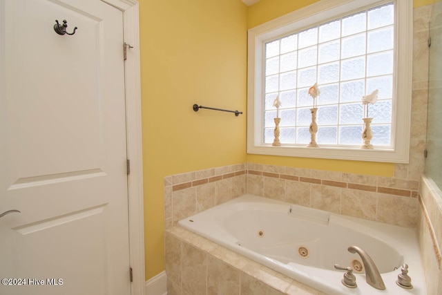 bathroom with a relaxing tiled tub and a healthy amount of sunlight