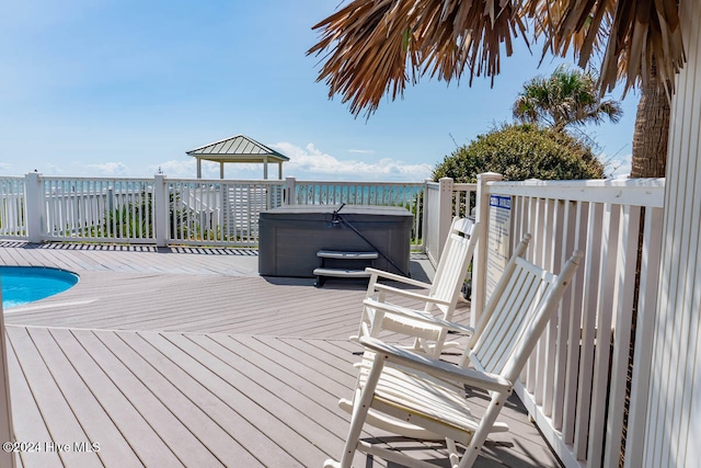 deck featuring a water view and a swimming pool with hot tub