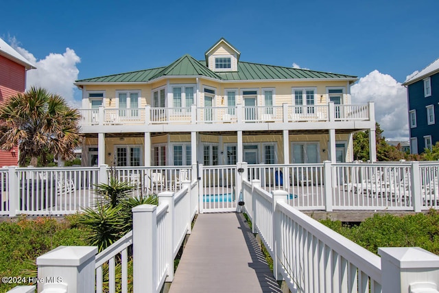 back of property featuring a fenced in pool and a balcony