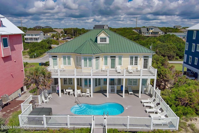 rear view of property with a patio, a fenced in pool, and a balcony