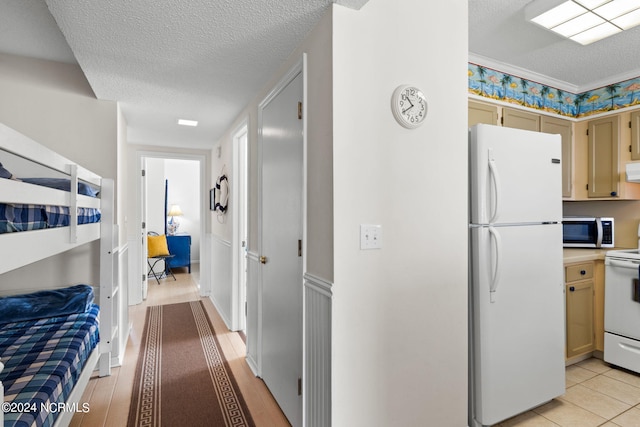 kitchen featuring light hardwood / wood-style flooring, a textured ceiling, and white appliances