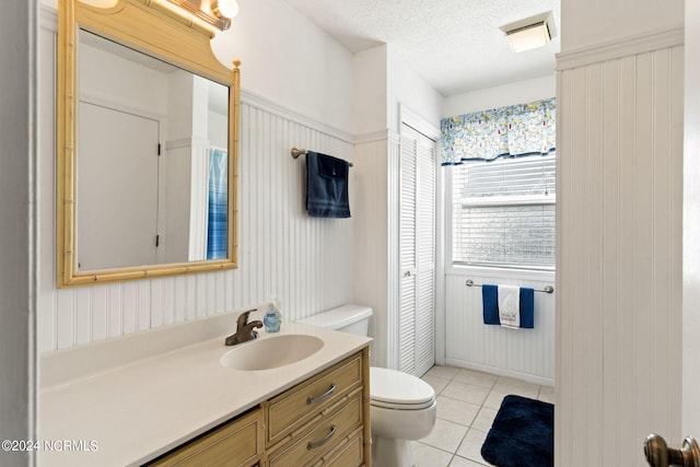 bathroom featuring vanity, a textured ceiling, toilet, and tile patterned flooring