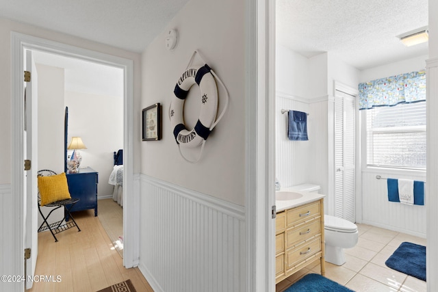 bathroom featuring vanity, a textured ceiling, hardwood / wood-style flooring, and toilet