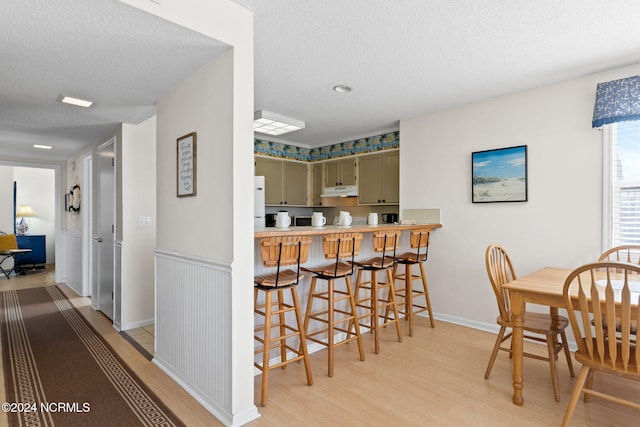 dining space with light hardwood / wood-style flooring and a textured ceiling