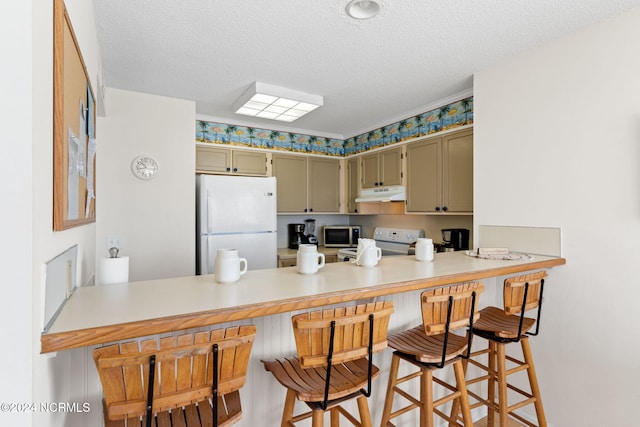 kitchen with kitchen peninsula, stainless steel appliances, a breakfast bar, green cabinetry, and a textured ceiling