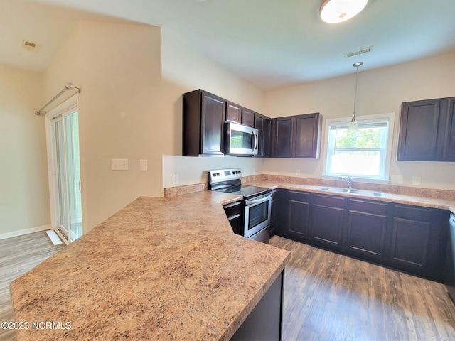 kitchen with sink, kitchen peninsula, light hardwood / wood-style floors, stainless steel appliances, and pendant lighting