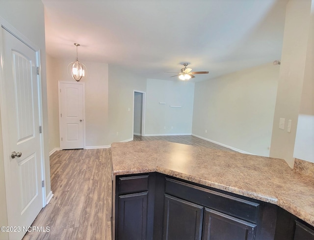 kitchen with wood-type flooring, decorative light fixtures, and ceiling fan with notable chandelier